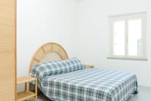 a bed with a plaid blanket and a mirror at Villa Antonia, 300 metres from the sea in Porto Ottiolu