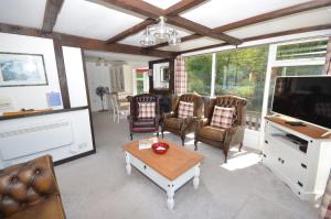 a living room with chairs and a tv and a table at The Willows in the center of the village in Horning in Horning