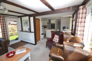 a living room with leather furniture and a kitchen at The Willows in the center of the village in Horning in Horning