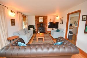 un soggiorno con divano in pelle e camino di Wherry Cottage in Irstead on the Norfolk Broads a Neatishead