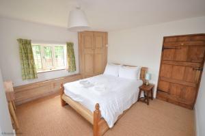 una camera da letto con un letto con lenzuola bianche e una finestra di Wherry Cottage in Irstead on the Norfolk Broads a Neatishead