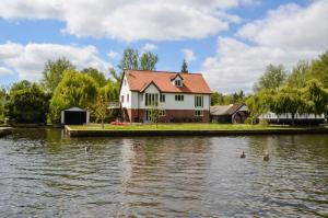 una casa su un molo vicino a un corpo d'acqua di The Willows Wroxham a Wroxham