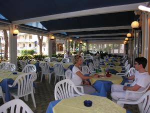 un grupo de personas sentadas en mesas en un restaurante en Hotel Garni Tahiti en Bibione