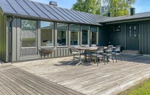 哈尔姆斯塔德Nice Home In Halmstad With Wifi的房屋内带桌椅的木制甲板
