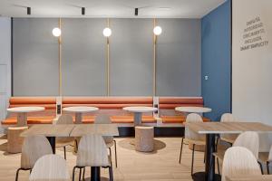 una habitación con mesas, sillas y un banco en B&B HOTEL Madrid Alcorcón, en Alcorcón