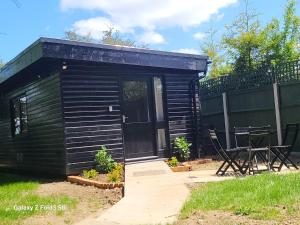 a small cabin with a door and a table and chairs at Hawthorne Barn in Lingwood