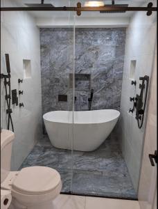 a bathroom with a white tub and a toilet at Luxury Apt in Passaic +17 photos