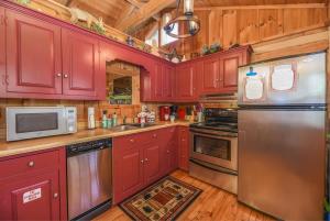 une cuisine avec des armoires rouges et des appareils en acier inoxydable dans l'établissement View! Cozy, Private, Fireplace, Hot Tub Log Cabin, Honeymoon!, à Sevierville