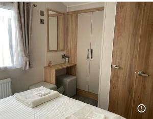 a bedroom with a bed with a mirror and a cabinet at Willerby lamberhurst in Westgate on Sea +2 photos