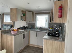 a kitchen with white cabinets and a stove top oven at Willerby lamberhurst in Westgate-on-Sea