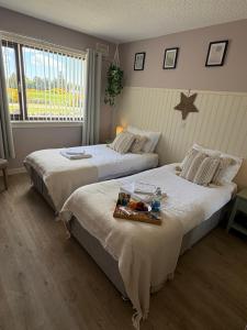 two beds in a bedroom with a tray of food at Carnegie Lodgings, Tain in Tain