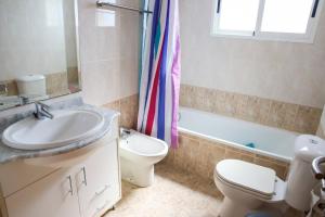 a bathroom with a sink and a toilet and a tub at Atico Piles in Piles +5 photos