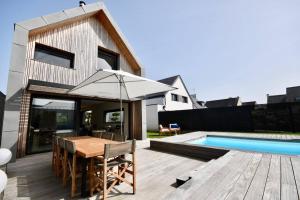 Un patio trasero con una mesa de madera y una piscina. en Kerguille, villa avec piscine, en La Trinité-sur-Mer