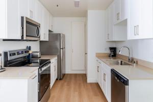 een keuken met witte kasten en een roestvrijstalen koelkast bij Blueground Shoreline West pool nr Shoreline Park SFO-1858 in San Francisco +14 foto's