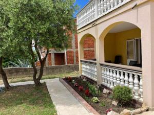 a porch of a house with a tree and flowers at Holiday Home Bella 1 & Bella 2 in Povljana