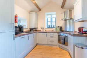 a large kitchen with white cabinets and a window at The Milking House - Llyn Peninsula in Nefyn +26 photos