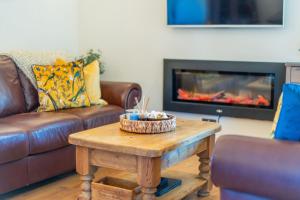 a living room with a couch and a coffee table with a fireplace at The Milking House - Llyn Peninsula in Nefyn