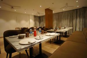 a dining room with long tables and chairs with plates at Mumbai House Express Udaipur in Udaipur