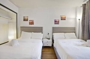 西纽约3BR Skyline Apt in Bustling District I Great Value NJ5的卧室设有两张床,拥有白色的墙壁和木地板