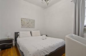 西纽约3BR Skyline Apt in Bustling District I Great Value NJ5的卧室里有一张铺着白色床单的床和一扇窗户 更多5张照片