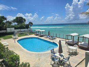 a swimming pool with the ocean in the background at 5 St Lawrence Beach Condo in Christ Church