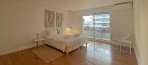 a white bedroom with a bed and a large window at YES! Incrível Vista Piscina T2 HsR Vilamarina in Vilamoura
