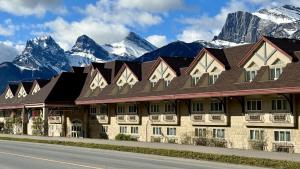 a hotel with snow covered mountains in the background at Canmore Inn & Suites in Canmore