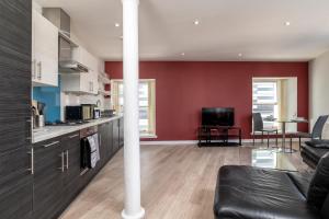 a kitchen with red walls and a living room at Central comfort and explore nearby cafes in Aberdeen
