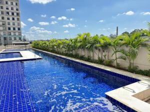 a large swimming pool with palm trees and a building at Ape Completo em Osasco - 15 min de Pinheiros in Osasco