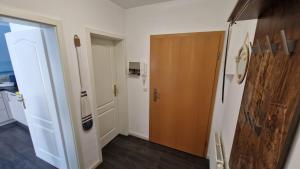a hallway with a wooden door and a kitchen at Ostseeeule in Graal-Müritz +24 photos