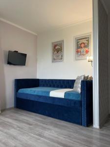 a bedroom with a blue couch and a tv at Azur Villa in Balatonalmádi