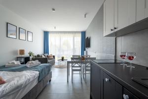 a room with a bed and a kitchen with wine glasses at Apartamenty Bellamaya - Kapitanska 8 in Grzybowo