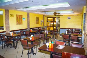 a restaurant with wooden tables and chairs and yellow walls at new raya hotel in Nairobi