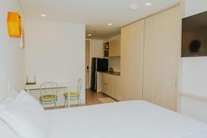 ein Schlafzimmer mit einem weißen Bett und einer Küche in der Unterkunft Estudio en Usaquén cerca a la Fundación Santa Fe ! in Bogotá