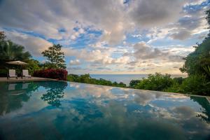 a swimming pool with a view of the ocean at RESOL Secluded Ocean-view luxury in the Jungle in Uvita