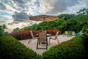 a table and chairs with an umbrella on a patio at RESOL Secluded Ocean-view luxury in the Jungle in Uvita