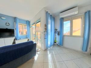 a living room with a blue couch and windows at Modern Seaview Townhouse - Workcation friendly in Orosei