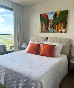 a bedroom with a large white bed with orange pillows at Brand New Apt Pool & City Views in Cartagena de Indias +41 photos