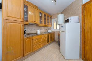 a kitchen with wooden cabinets and a white refrigerator at 2 Bed Bungalow El Tratxo in El Campello