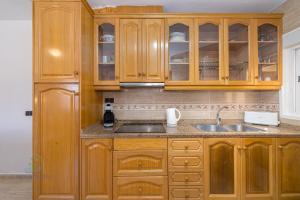 a kitchen with wooden cabinets and a sink at 2 Bed Bungalow El Tratxo in El Campello