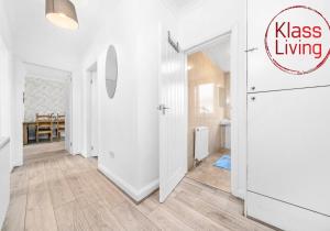 un corridoio con pareti bianche, pavimenti in legno e una porta di Anderson Apartment by Klass Living Motherwell a Motherwell