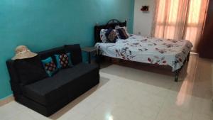 a bedroom with a bed and a couch and a chair at Palms Cosy affordable homely flat in Arpora