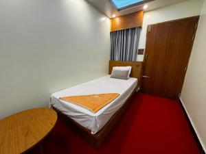 a small room with a bed and a wooden door at Hotel Al-Hayat Abasik in Dhaka
