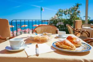 a table with a plate of pastries and cups on it at Hotel Rivamare in Ischia