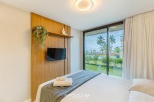 ein Schlafzimmer mit einem Bett, einem Fernseher und einem Fenster in der Unterkunft Aptos em Cond. c/ piscina à Beira da Praia em Ilhéus - PET in Pontal + 46 Fotos