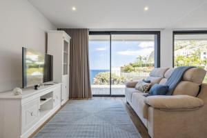 un salon avec un canapé et une télévision à écran plat dans l'établissement Atlantic Gem by Homie, à Câmara de Lobos