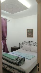 a bedroom with a bed with a green blanket on it at Appartement Familial Près d'aéroport Ibn Batouta Tanger in Tangier