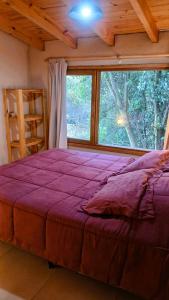 a bedroom with a purple bed and a large window at Cabaña en Villa Los Coihues II in San Carlos de Bariloche