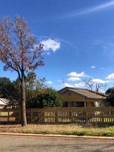 ein Holzzaun vor einem Haus mit einem Baum in der Unterkunft Michelle Cottage in Southgate