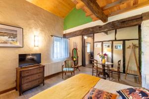 a bedroom with a bed and a tv and a table at La Maison de Yûka in Plieux
